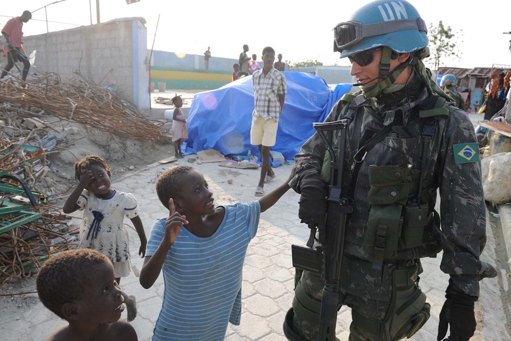100316-N-9116F-001.PORT-AU-PRINCE, Haiti (March 16, 2010) A Brazilian U.N. peacekeeper walks with Haitian children during a patrol in Cite Soleil, a section of Port-au-Prince. Several U.S. and international military and non-governmental agencies are conducting humanitarian and disaster relief operations as part of Operation Unified Response after a 7.0-magnitude earthquake caused severe damage in and around Port-au-Prince, Haiti Jan. 12. (U.S. Navy photo by Mass Communication Specialist 1st Class David A. Frech/Released)