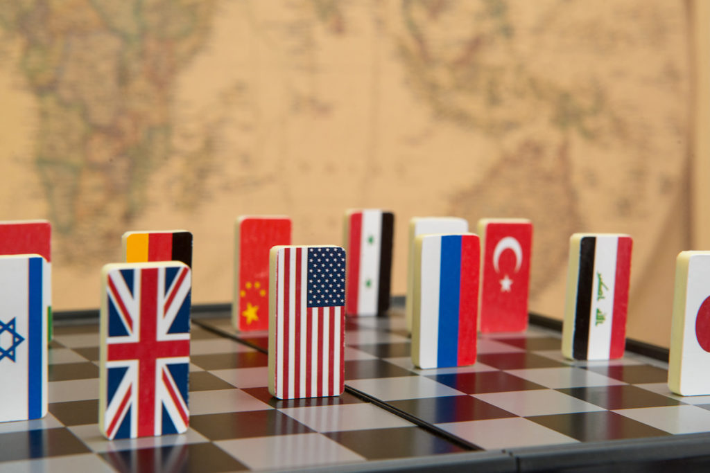 symbols of countries on the chessboard against against the background the political map of the world