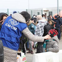 IOM Ukraine volunteer helping to direct two children at the border
