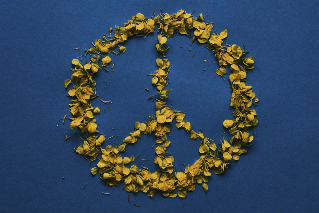 Peace symbol made of yellow leaves on a blue background
