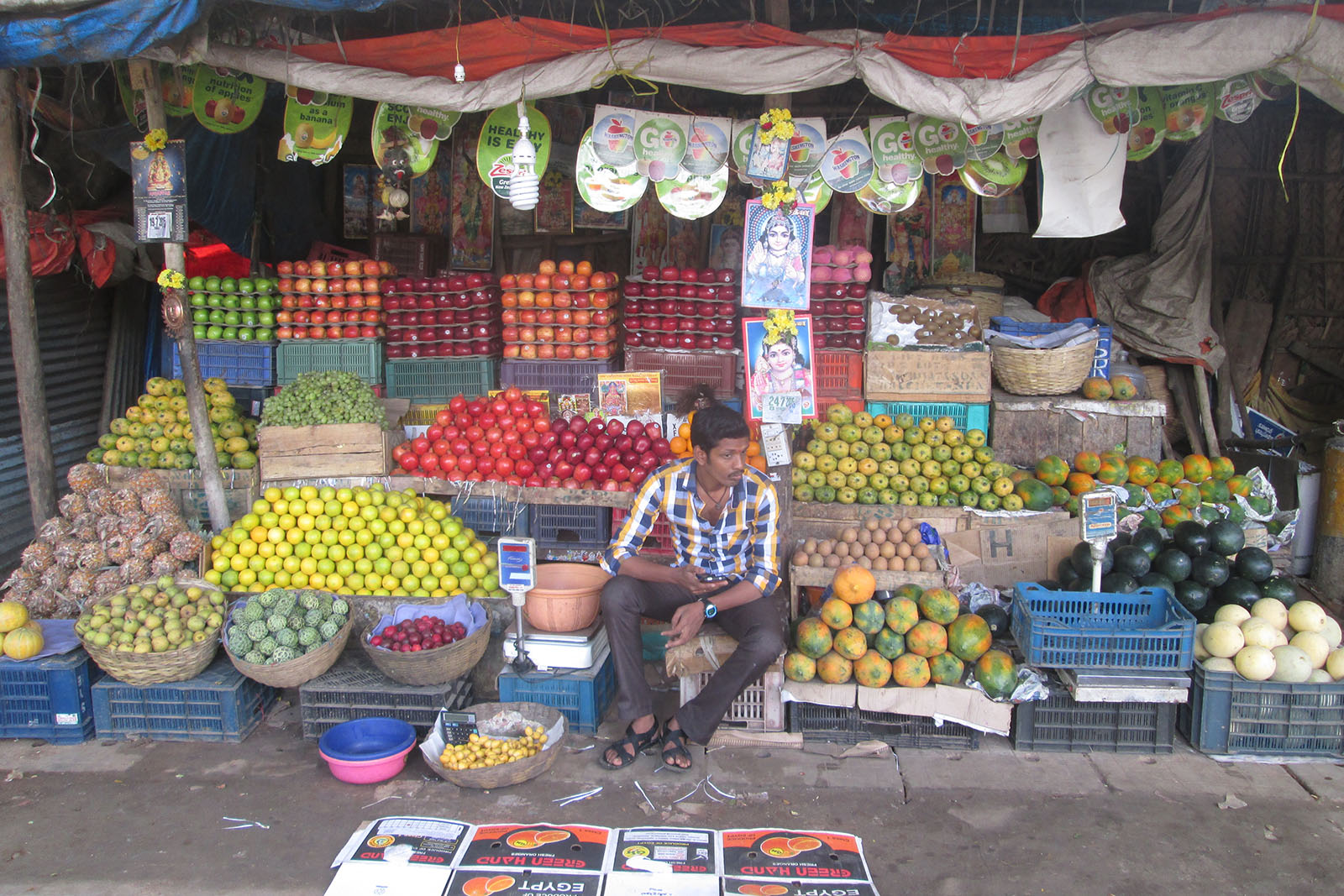 Man sitting between fruit at a market stand