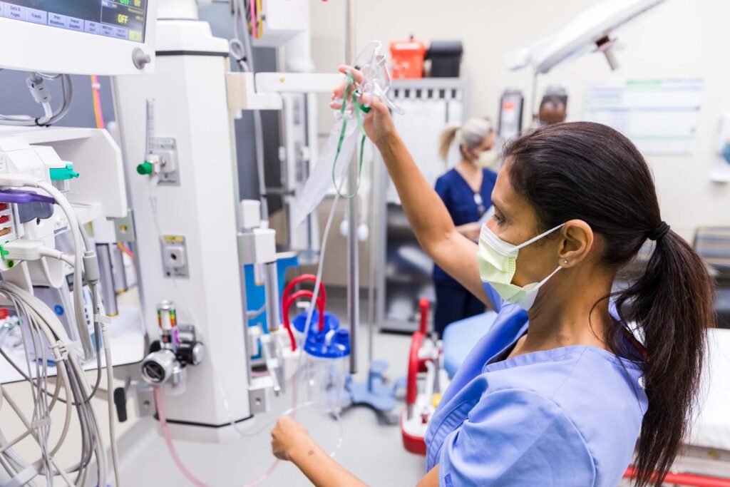Female nurse with mask checks medical equipment in ER