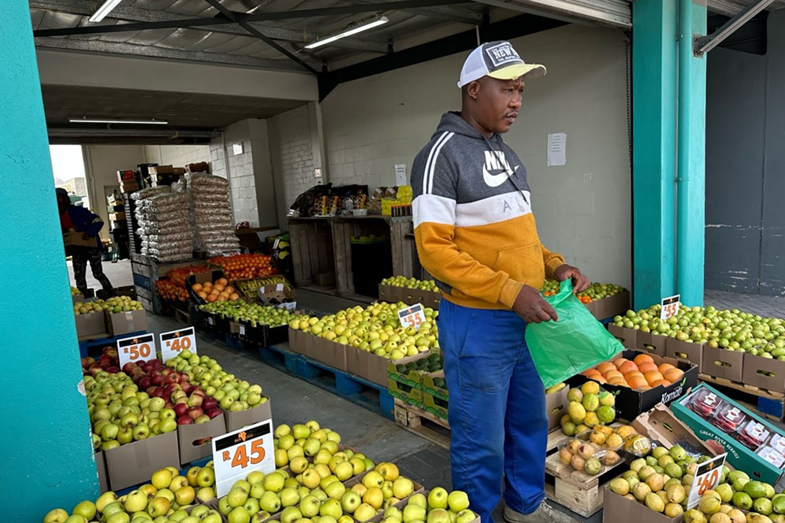 Man standing in the middle of a market of apples.