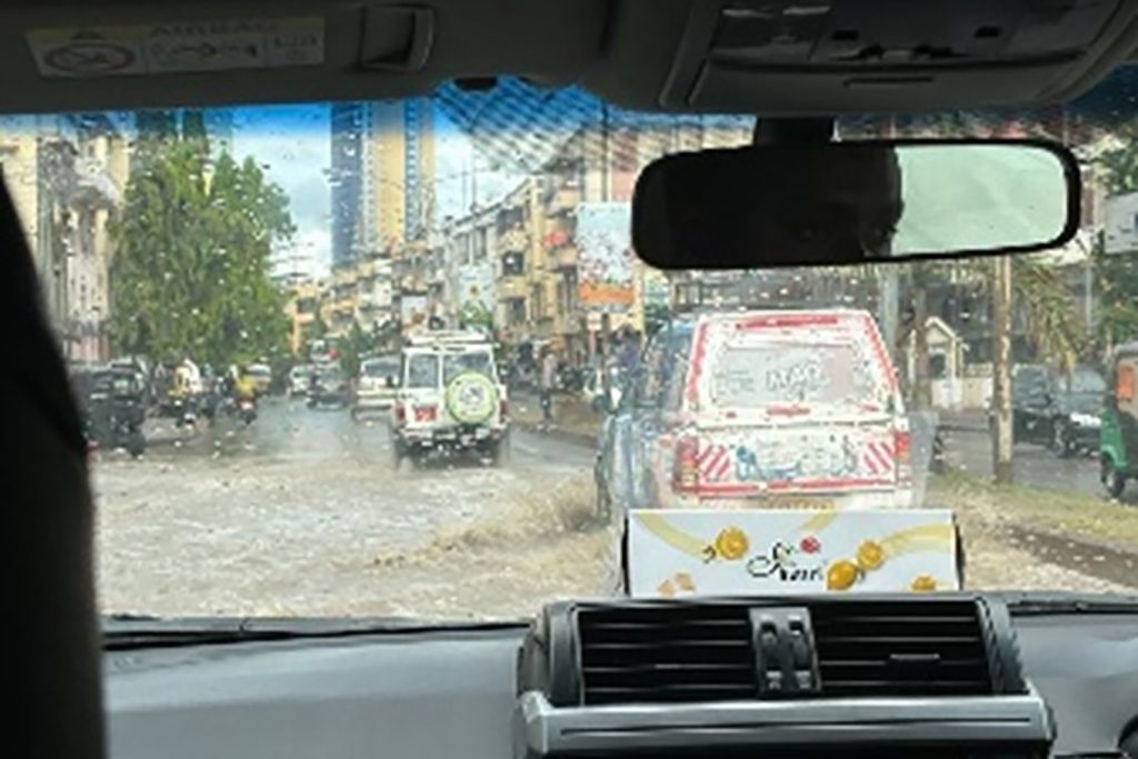 Photo taken through a car windshield of cars driving through flooded streets.. Driving from the airport, arriving in Dar es Salaam during the peak of Niño’s storms.