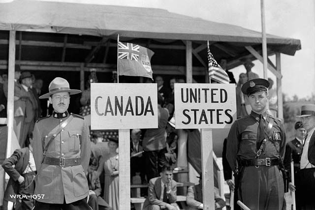 Police officers standing next to signs saying Canada and United States.